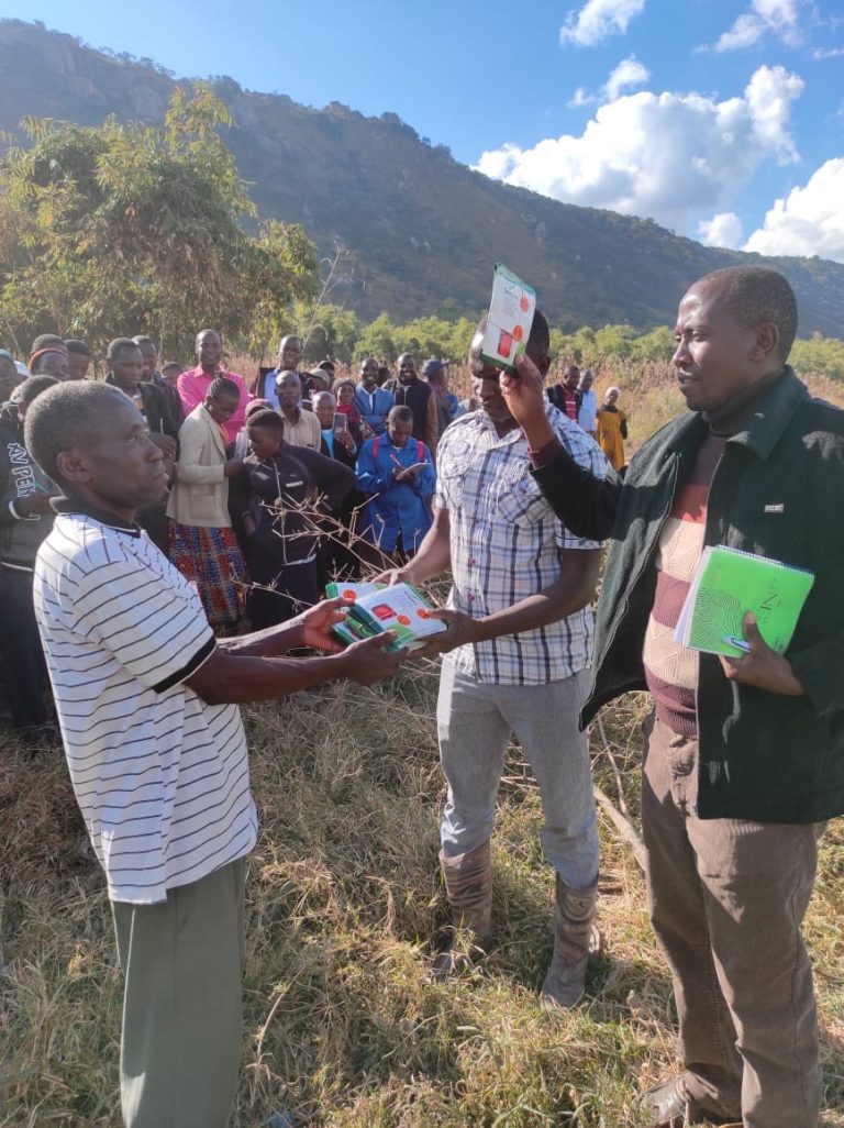 Participants in Tanzania sharing materials during a group training session, focusing on overcoming challenges in large group learning