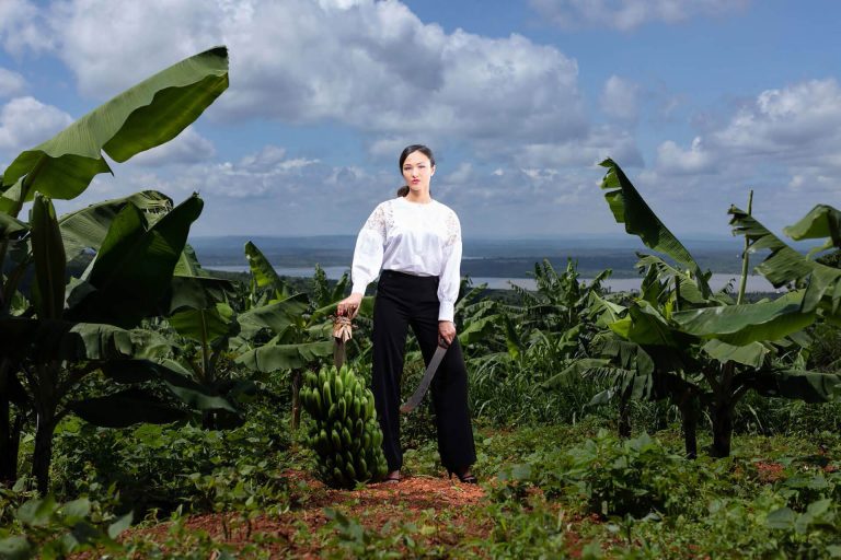 Lady in banana field with bunch of bananas and machette